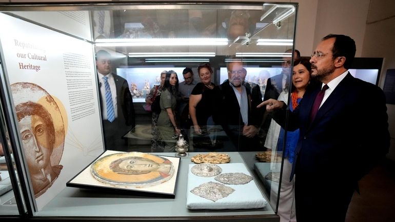 Cyprus' President Nikos Christodoulides, right, stands in front of an...