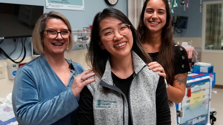 Andy Hoang, a recent nursing graduate, center, poses with co-workers...