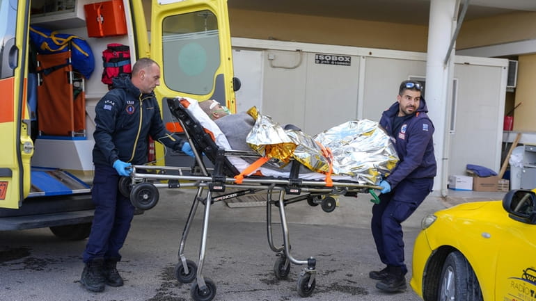 Paramedics transfer a survivor of a shipwreck at a hospital,...