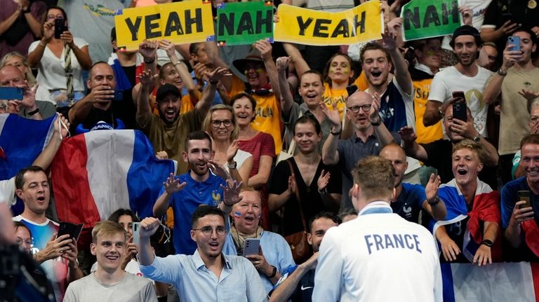 Supporters of gold medalist Leon Marchand cheer during the medal...