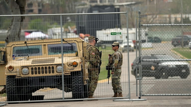 Members of the National Guard stand at a gate to...
