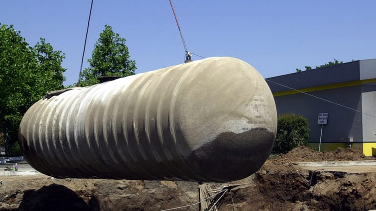 Workers remove a 10,000-gallon underground gasoline storage tank to be...