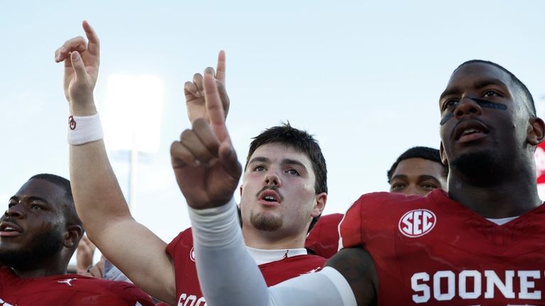 Oklahoma quarterback Jackson Arnold and linebacker Kobie McKinzie sing the...