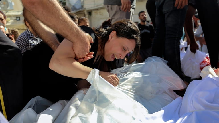 A Palestinian woman mourns over the bodies of her relatives...
