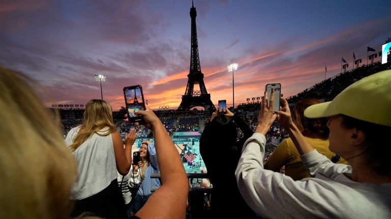 Spectators photograph a colorful sunset at Eiffel Tower Stadium prior...