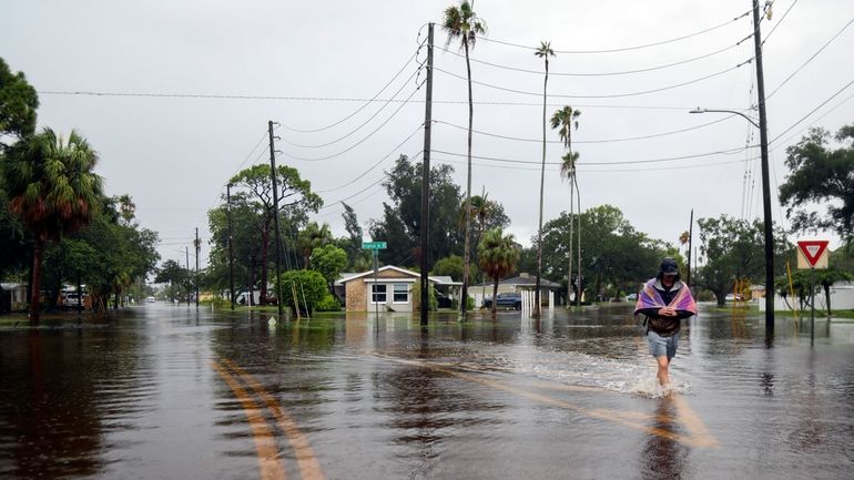 Carter Grooms, 25, of Tampa, wades through the streets in...