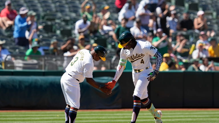 Oakland Athletics' Lawrence Butler, right, celebrates with third base coach...