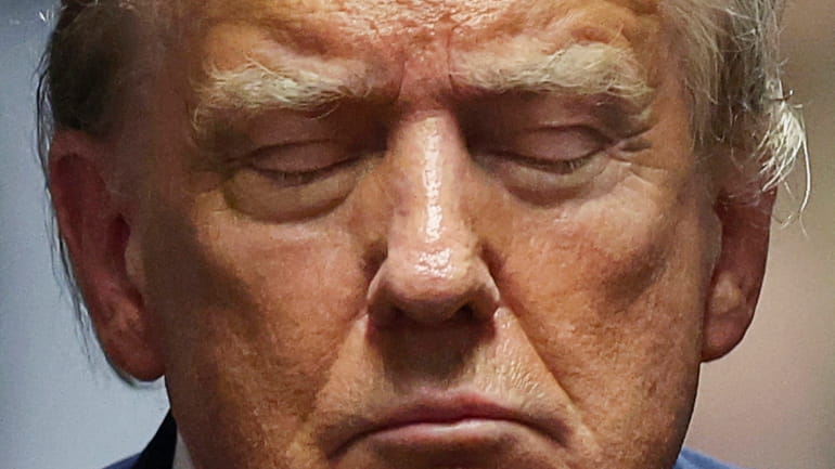 Former President Donald Trump closes his eyes during his trial...