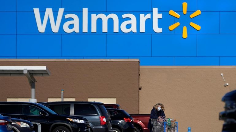 A woman wheels a cart with her purchases out of...