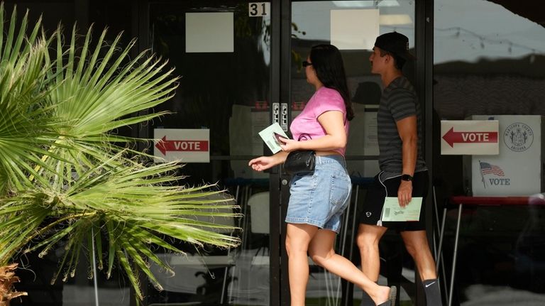 Voters walk to a voting precinct prior to dropping of...