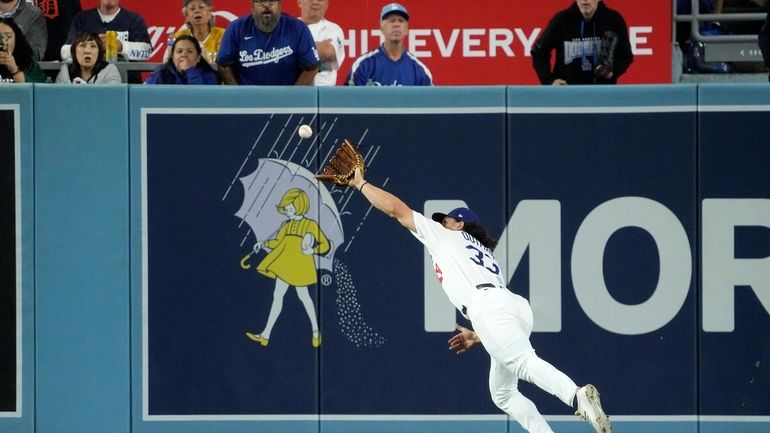 Los Angeles Dodgers center fielder James Outman makes a catch...