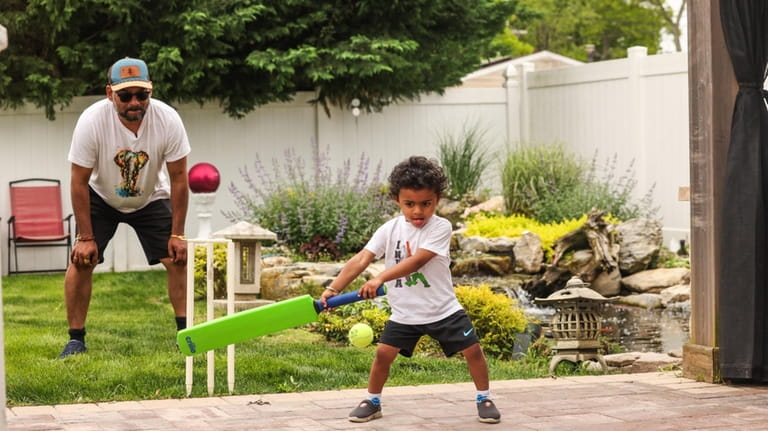 Vijay Raghunath, 3, right, plays cricket with his father, Raghunath,...