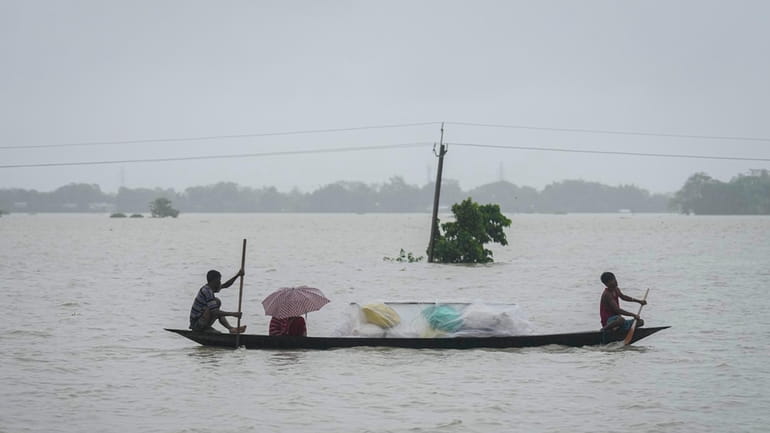 Flood affected people travel with their belongings through flood waters...