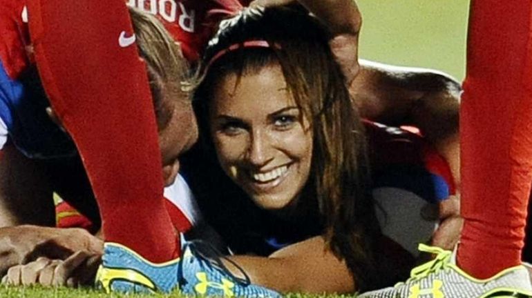 Team USA's Alex Morgan smiles as her team piles on...