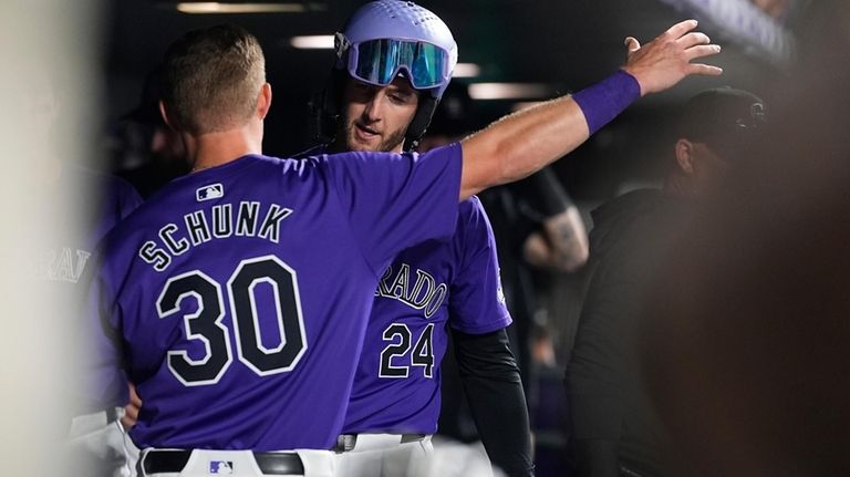 Colorado Rockies' Aaron Schunk (30) hugs Ryan McMahon (24) who...