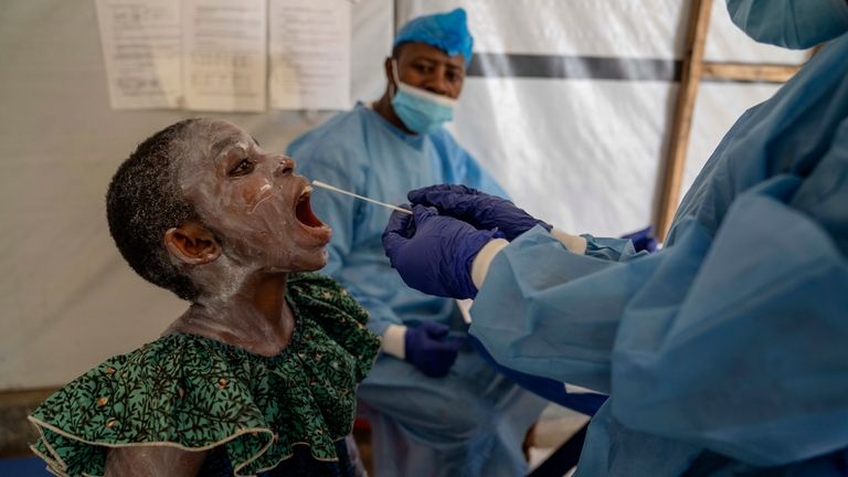 A health worker takes a saliva sample from Lucie Habimana,...