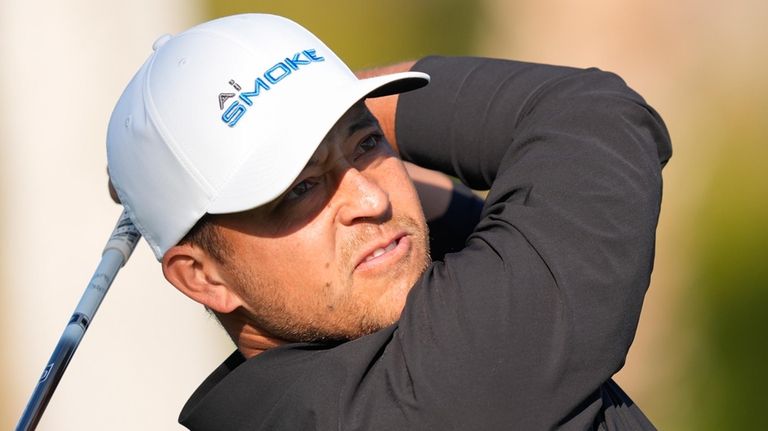 Xander Schauffele watches his tee shot on the first hole...