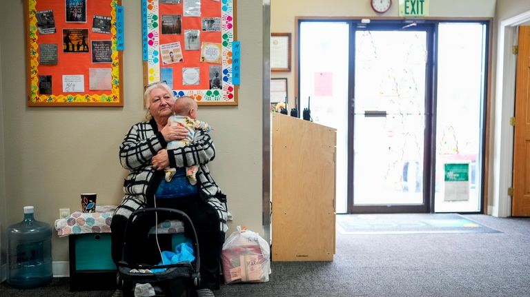 Kristine Bayne holds a grandchild as she waits for her...