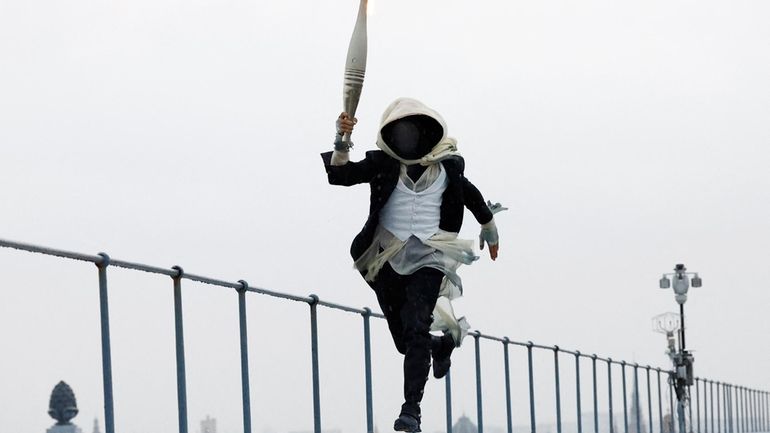 A torch bearer runs atop the Musee d'Orsay, in Paris,...