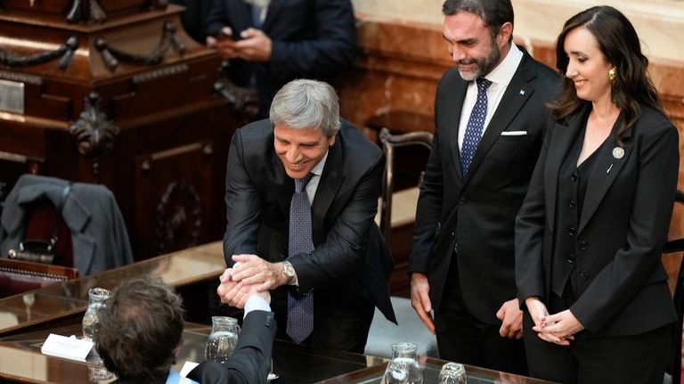 Argentina's Economy Minister Luis Caputo, second from left, greets Argentina's...