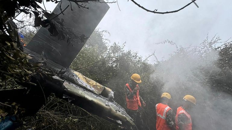 Rescuers work at the site of a helicopter that crashed...