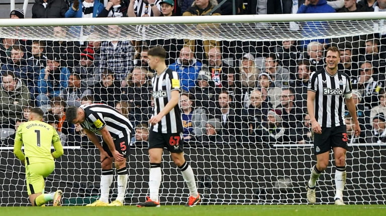 Newcastle United's Dan Burn, right, and teammates appear dejected after...
