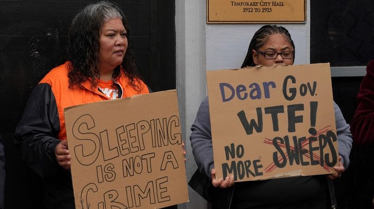 Activists hold signs at a news conference opposing Mayor London...