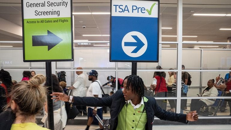 An aiport employee helps travelers navigate long lines for security...