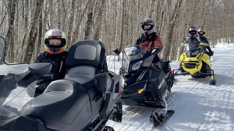 A group heads out on a guided snowmobile tour with...