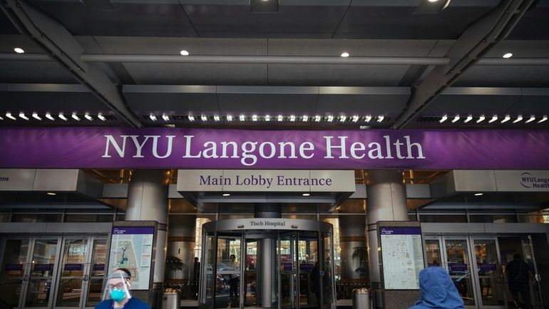 Health care workers walk in and out of the entrance...