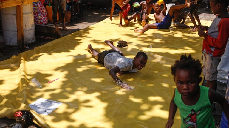 Children play on a slip-and-slide at a shelter for families...