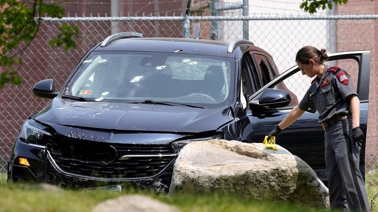 A Rhode Island state trooper places an evidence marker near...