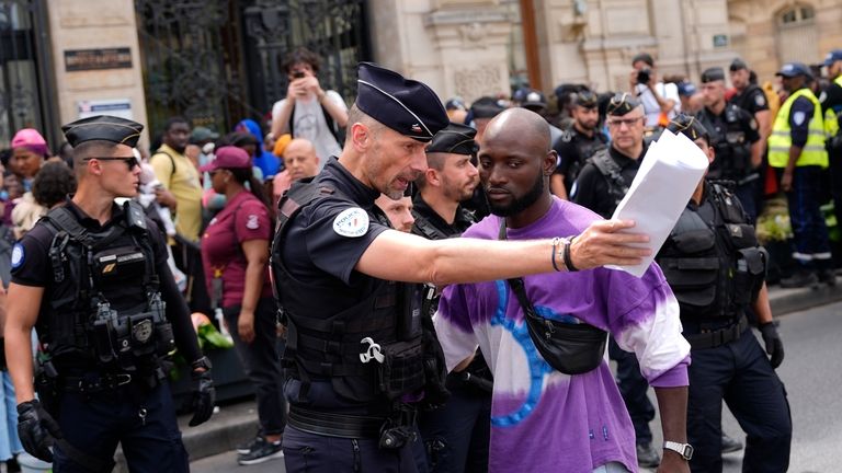 Police officers escort away man during a migrants' protest at...