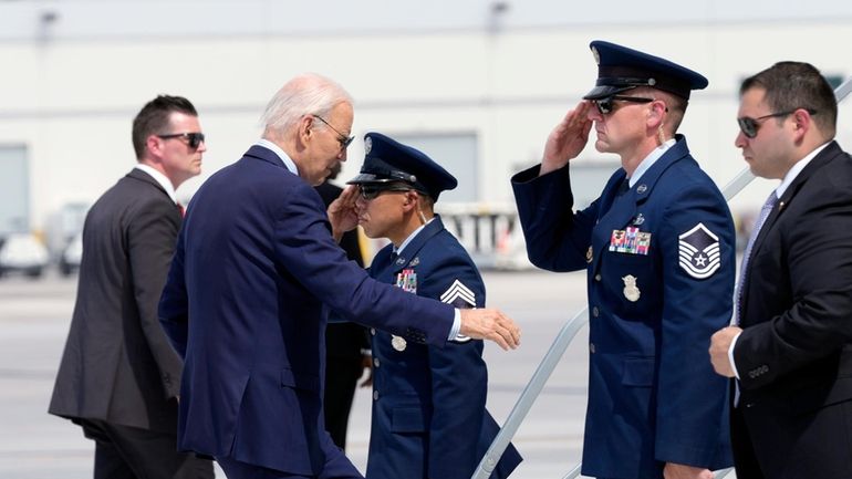 President Joe Biden walks up the steps of Air Force...