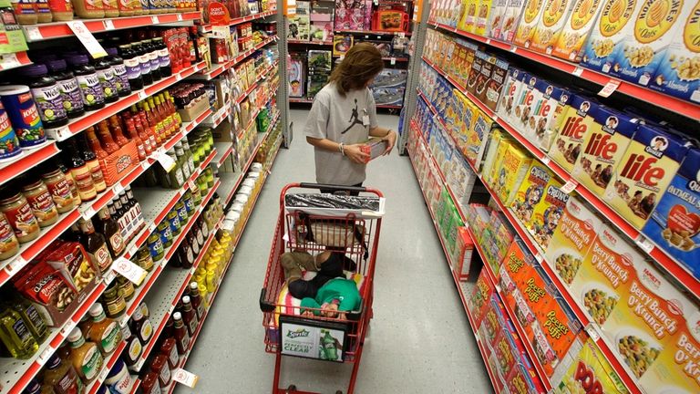 A woman looks at products in the aisle of a...