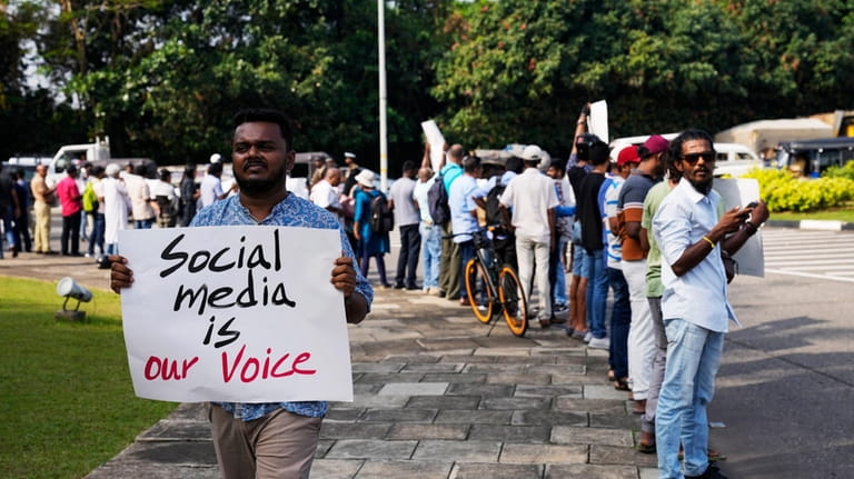 Sri Lankan social media activists hold placards with slogans against...