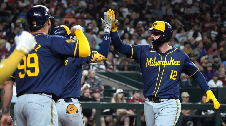 Milwaukee Brewers' Rhys Hoskins (12) celebrates with teammates after hitting...