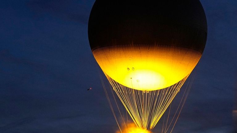 The balloon carrying the Olympic cauldron rises above Tuileries Garden...