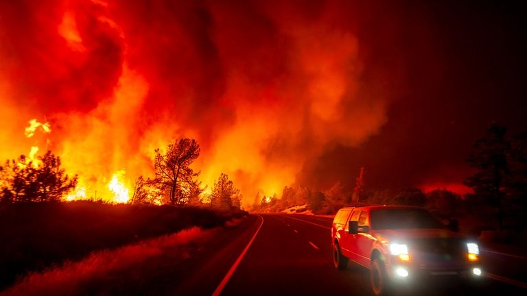 Smoke rises above the roadway as the Park Fire jumps...