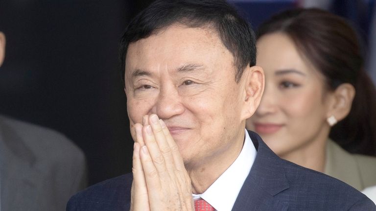 Thailand's former Prime Minister Thaksin Shinawatra greets his supporters as...