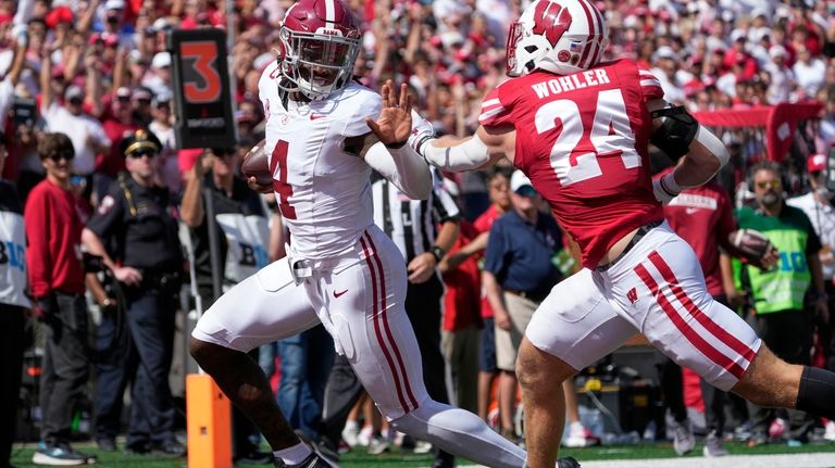 Alabama's Jalen Milroe (4) runs past Wisconsin's Hunter Wohler (24)...