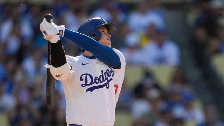 Los Angeles Dodgers designated hitter Shohei Ohtani watches his solo...