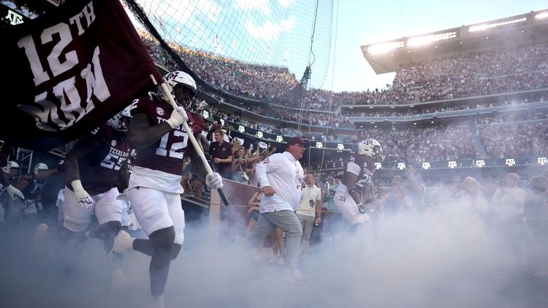 Texas A&M head coach Mike Elko leads his team on...