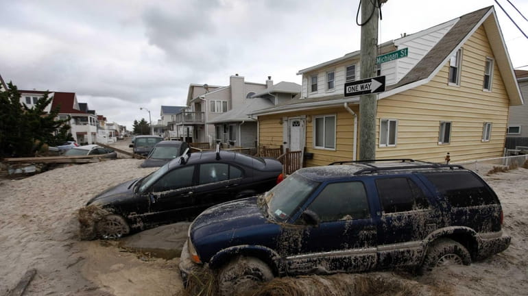 Cars lifted by floodwater in Long Beach are submerged in...