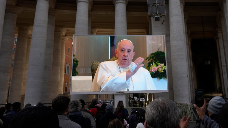 A giant screen broadcasts Pope Francis delivering his blessing during...