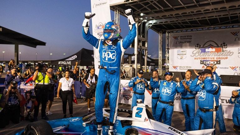 Josef Newgarden celebrates on top of his car after winning...