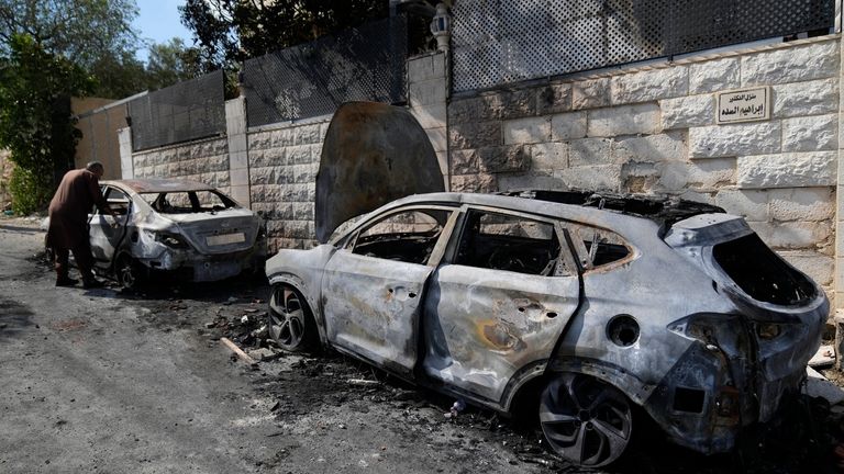 A Palestinian examines a torched vehicle, seen the morning after...