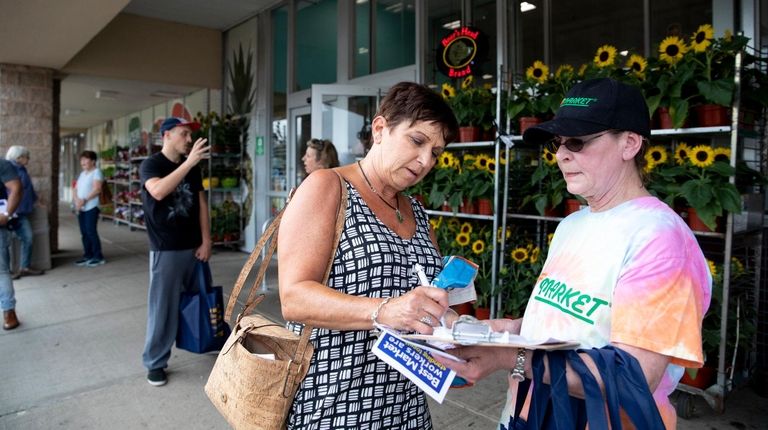 Christine Patty, left, of Huntington signs a petition held by...