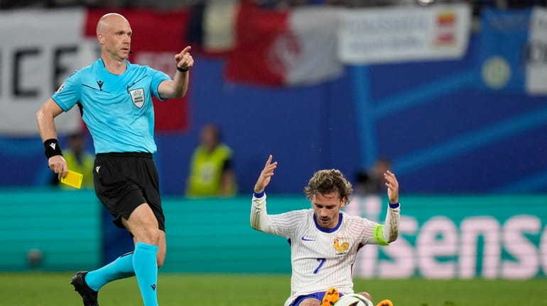 Referee Anthony Taylor of England, left, pulls out a yellow...