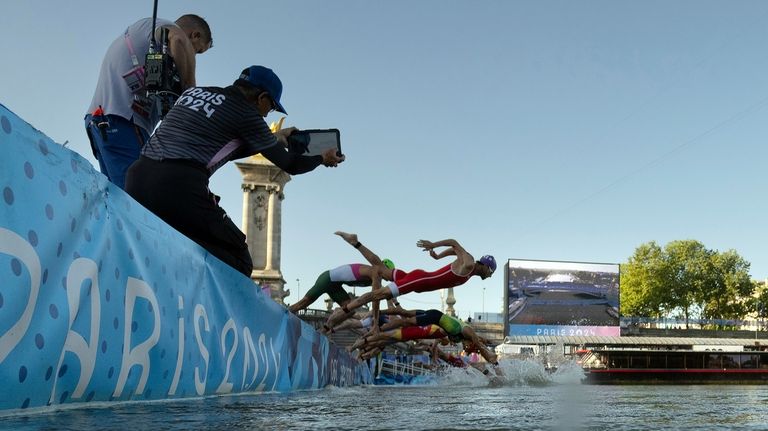 Athletes jump into the water to compete in the swimming...